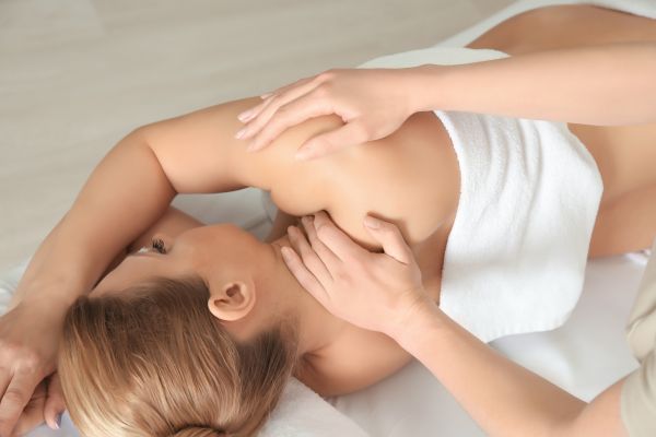 Doula gibt schwangeren Frau eine Schwangerschaftsmassage in Frankfurt. Die Schwangere liegt entspannt in Seitenlage auf einer bequemen Massageliege. 