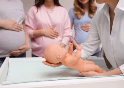 Schwangere Frauen im Säuglingspflegekurs beim Üben des Wickelns mit Puppe – Doula-Angebot in Frankfurt, Oberursel und Bad Homburg.