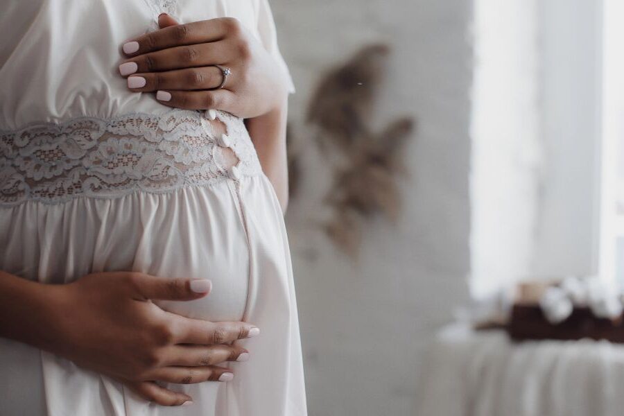 Schwangere Frau legt ihre Hände auf den Babybauch als Symbol für mentale Geburtsvorbereitung und Vertrauen in die Geburt.